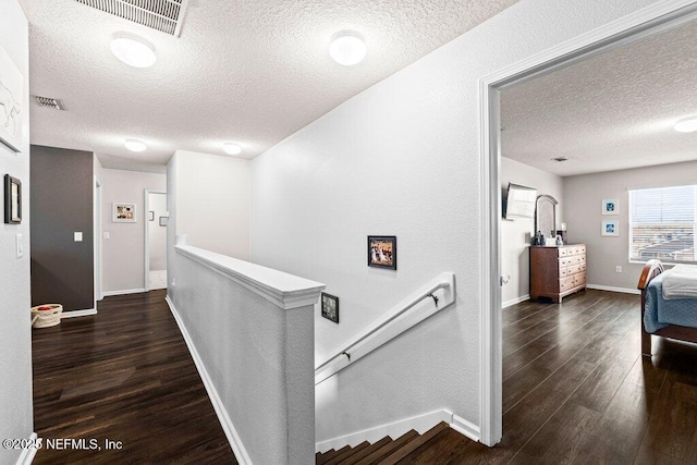 hall with dark wood-type flooring and a textured ceiling