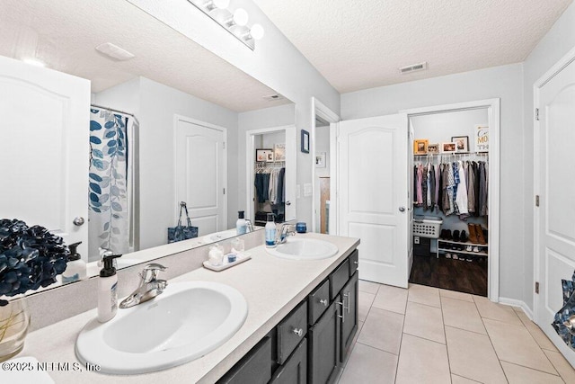 bathroom with a shower with curtain, vanity, tile patterned flooring, and a textured ceiling