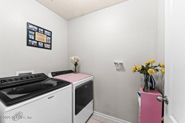 laundry area with light tile patterned flooring, washing machine and clothes dryer, and a textured ceiling