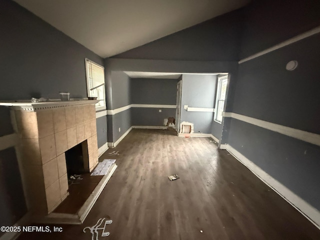 unfurnished living room with lofted ceiling, a tiled fireplace, and dark hardwood / wood-style floors