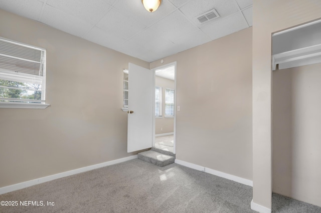 unfurnished bedroom featuring a paneled ceiling, carpet floors, and multiple windows