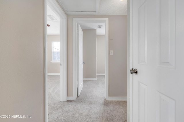 hall featuring light carpet and a textured ceiling