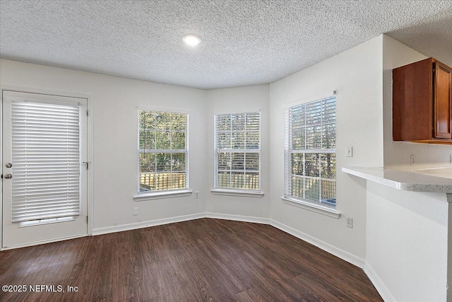 unfurnished dining area with plenty of natural light, dark hardwood / wood-style flooring, and a textured ceiling