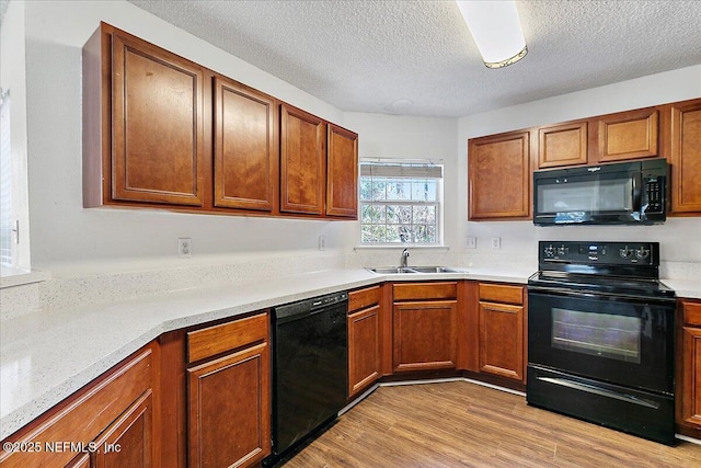 kitchen with sink, black appliances, light hardwood / wood-style floors, and a textured ceiling