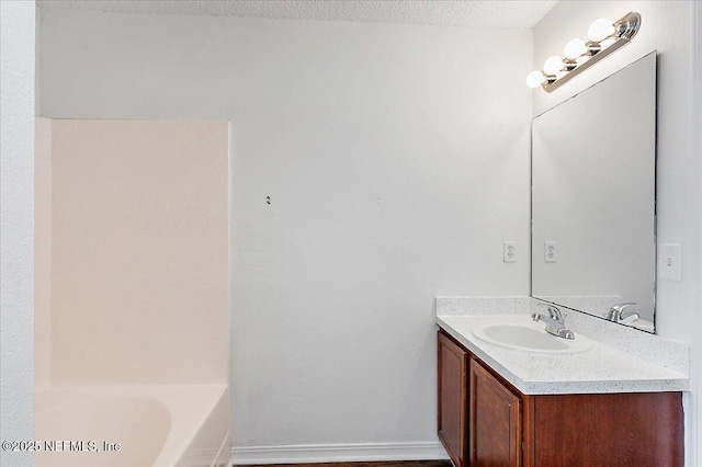 bathroom with vanity, a textured ceiling, and a tub