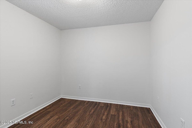 unfurnished room with dark wood-type flooring and a textured ceiling