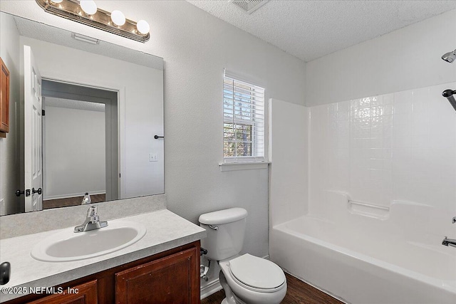 full bathroom featuring vanity, toilet, a textured ceiling, and washtub / shower combination