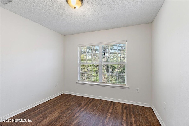 empty room featuring dark hardwood / wood-style floors and a textured ceiling