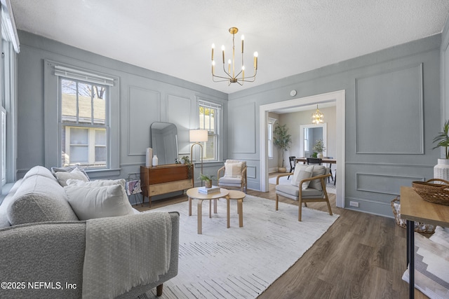 living room with dark wood-type flooring, a chandelier, and a textured ceiling