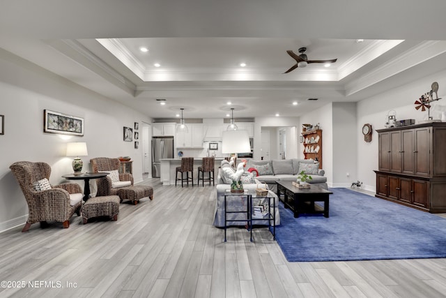 living room featuring light wood-type flooring, a tray ceiling, crown molding, and baseboards