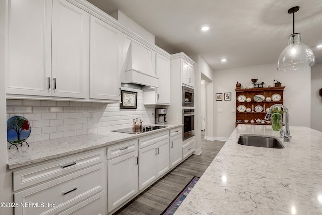 kitchen with stainless steel appliances, custom range hood, backsplash, white cabinetry, and a sink