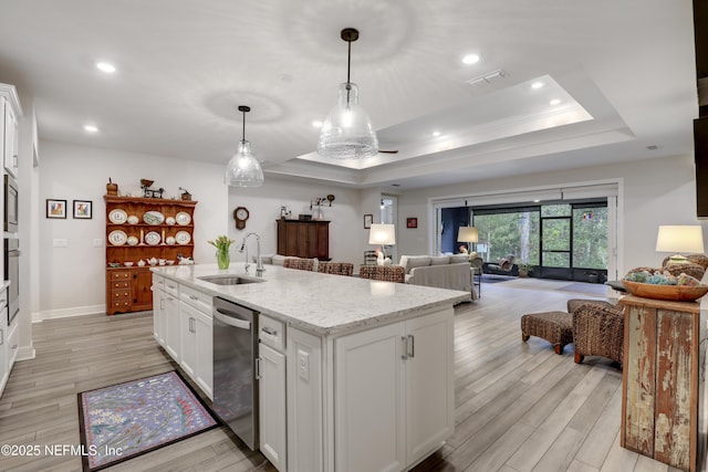 kitchen with appliances with stainless steel finishes, a raised ceiling, a sink, and light wood finished floors