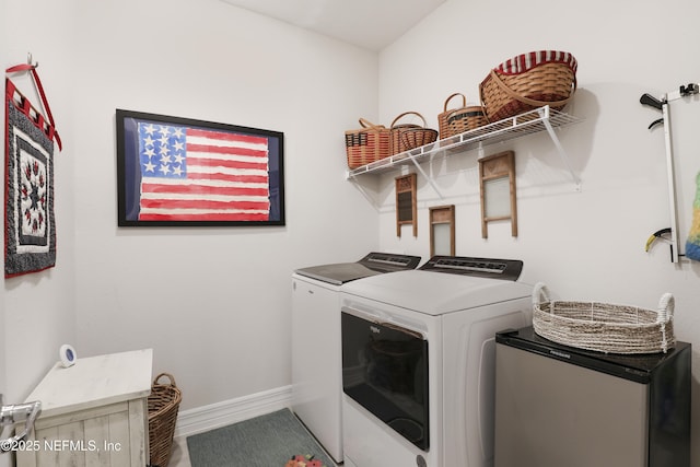 washroom featuring laundry area, baseboards, and separate washer and dryer