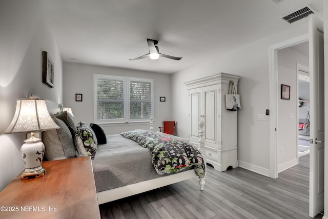 bedroom featuring baseboards, visible vents, ceiling fan, and wood finished floors