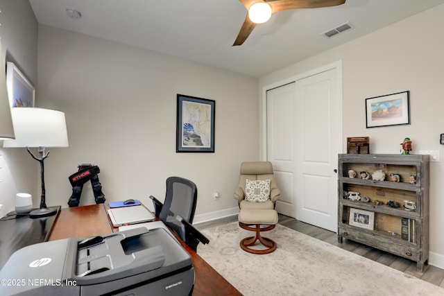 office space featuring a ceiling fan, baseboards, visible vents, and wood finished floors