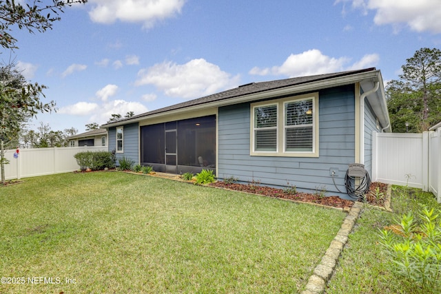 back of house featuring a sunroom, a fenced backyard, and a yard