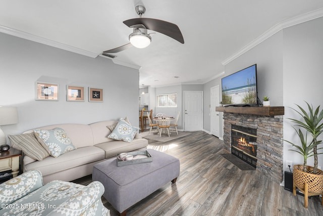 living room with a stone fireplace, ornamental molding, dark hardwood / wood-style floors, and ceiling fan