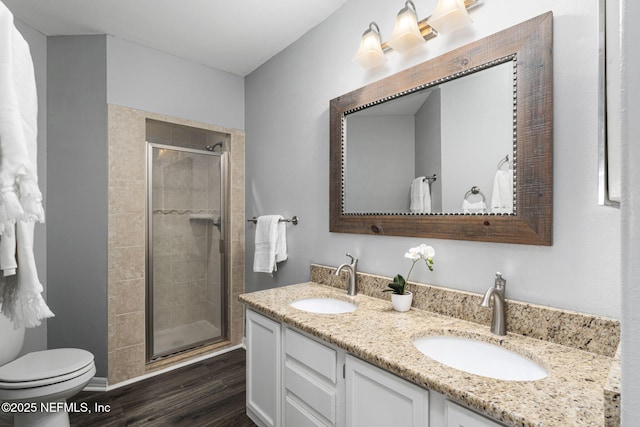 bathroom featuring vanity, hardwood / wood-style flooring, a shower with door, and toilet