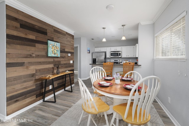 dining space with ornamental molding, hardwood / wood-style floors, and wood walls