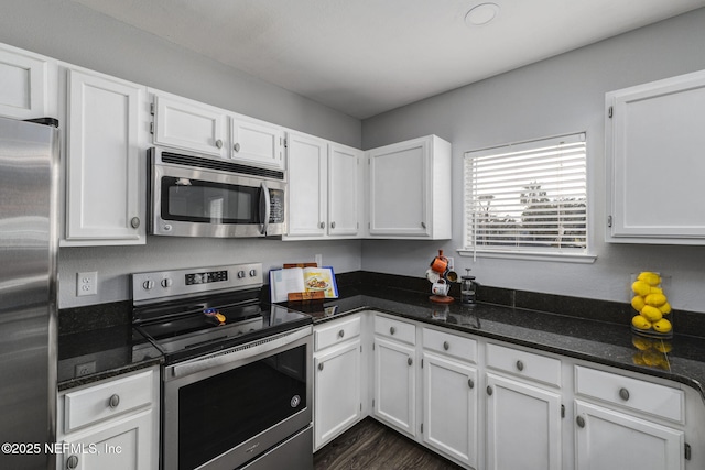 kitchen with appliances with stainless steel finishes, dark hardwood / wood-style floors, dark stone counters, and white cabinets