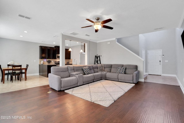 living room with dark wood-type flooring, ceiling fan, and sink