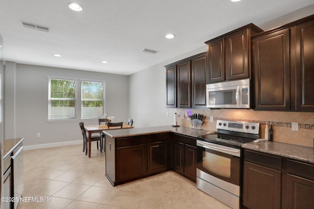 kitchen with stainless steel appliances, tasteful backsplash, dark brown cabinetry, and kitchen peninsula