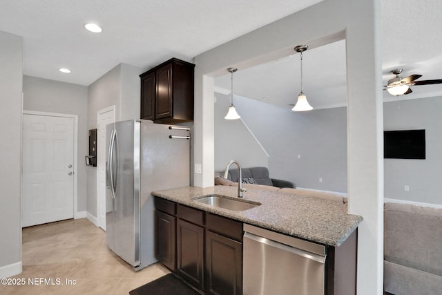 kitchen with sink, ceiling fan, appliances with stainless steel finishes, dark brown cabinetry, and light stone counters