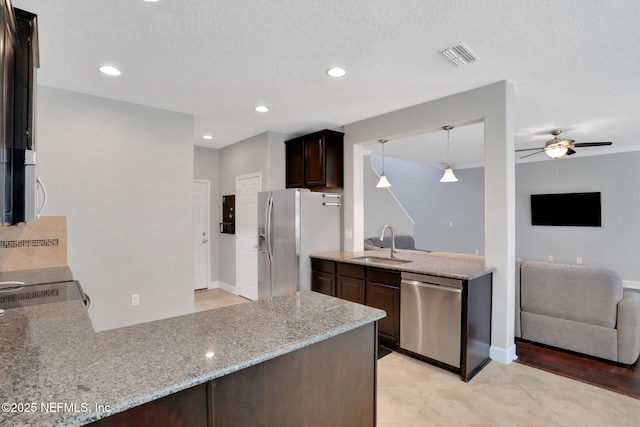 kitchen featuring sink, dark brown cabinets, stainless steel appliances, decorative light fixtures, and kitchen peninsula