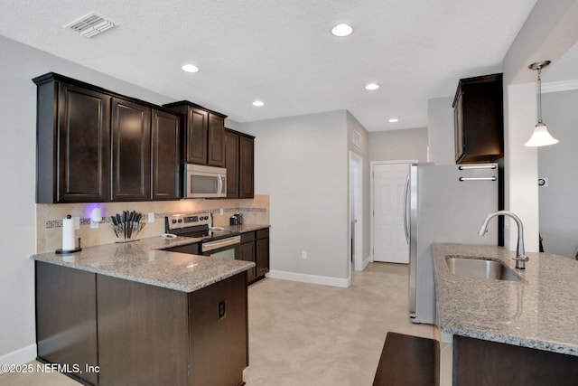 kitchen featuring pendant lighting, sink, kitchen peninsula, stainless steel appliances, and light stone countertops