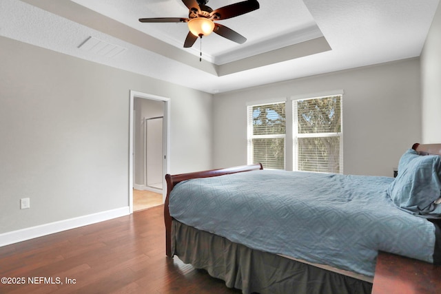 bedroom with ceiling fan, ornamental molding, dark hardwood / wood-style floors, and a raised ceiling