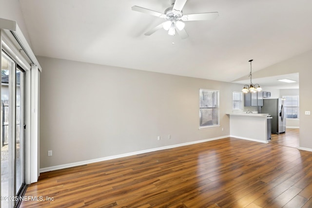 unfurnished living room featuring dark wood-type flooring, lofted ceiling, and ceiling fan with notable chandelier