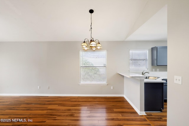 unfurnished dining area with an inviting chandelier, sink, vaulted ceiling, and dark hardwood / wood-style floors