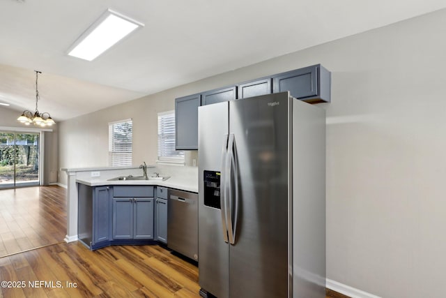 kitchen featuring sink, an inviting chandelier, hanging light fixtures, hardwood / wood-style floors, and stainless steel appliances