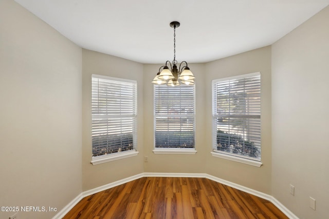 unfurnished room with a notable chandelier and hardwood / wood-style flooring