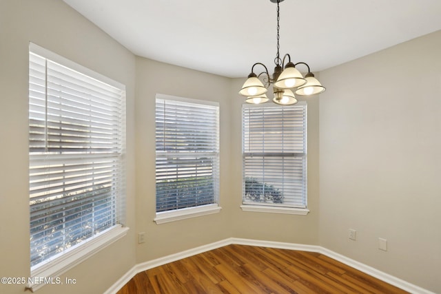 spare room with wood-type flooring and an inviting chandelier