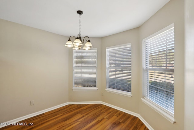 empty room featuring wood-type flooring and an inviting chandelier