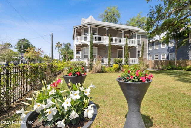 view of front of home featuring a balcony, a front yard, covered porch, and fence