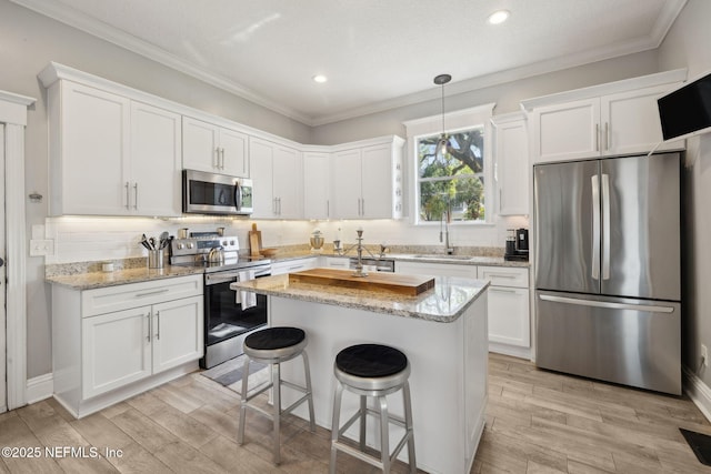 kitchen featuring a sink, white cabinetry, tasteful backsplash, appliances with stainless steel finishes, and light wood-type flooring