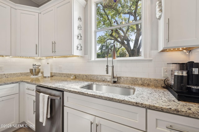kitchen featuring decorative backsplash, white cabinetry, a sink, and stainless steel dishwasher