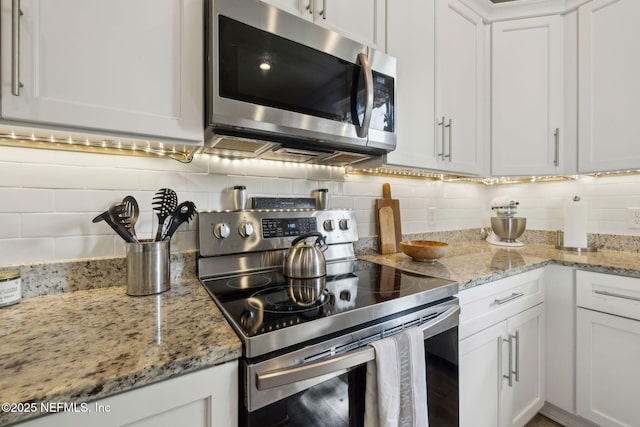 kitchen featuring backsplash, white cabinets, light stone countertops, and appliances with stainless steel finishes