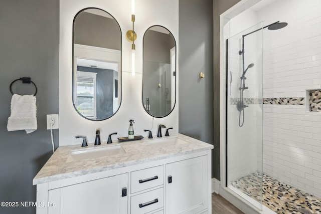 bathroom with double vanity, a sink, and tiled shower