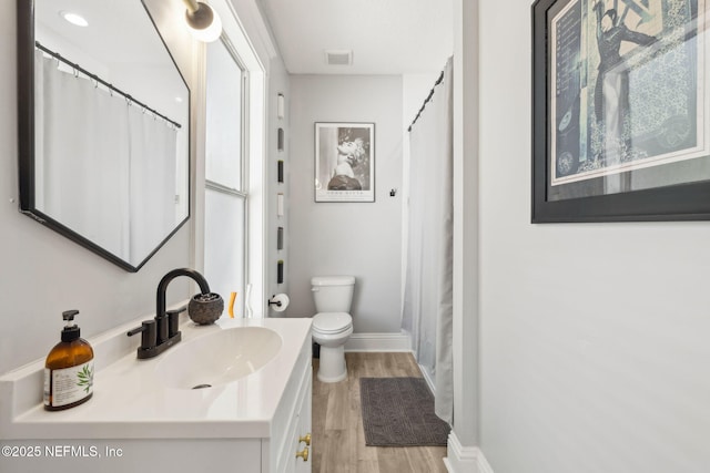 full bath with visible vents, baseboards, wood finished floors, toilet, and vanity