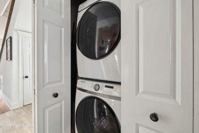 washroom with light wood-type flooring, stacked washer / drying machine, and laundry area