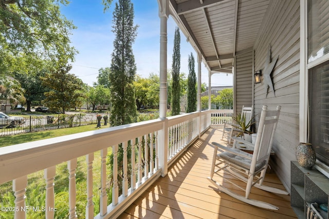 wooden terrace featuring fence and a porch