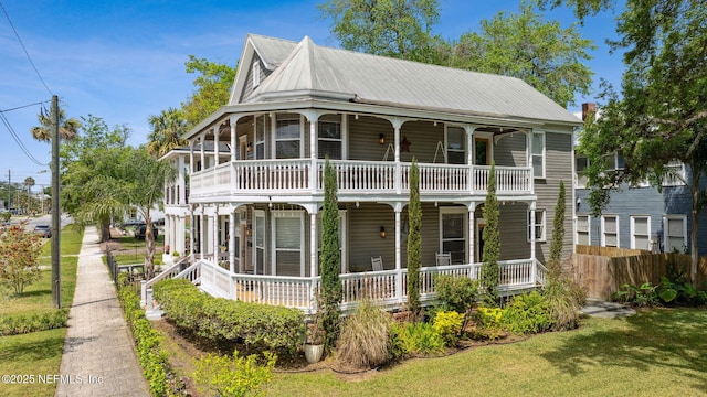 view of front of property featuring a porch, a front lawn, fence, and metal roof