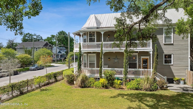 view of front of house featuring covered porch, fence, and a front lawn