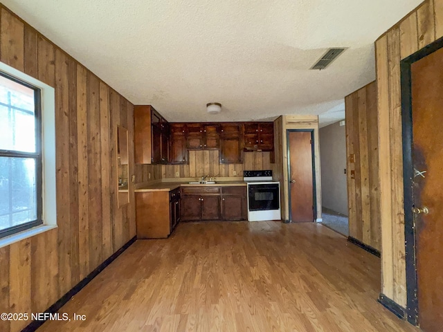 kitchen featuring wooden walls, sink, white range with electric cooktop, a textured ceiling, and light wood-type flooring