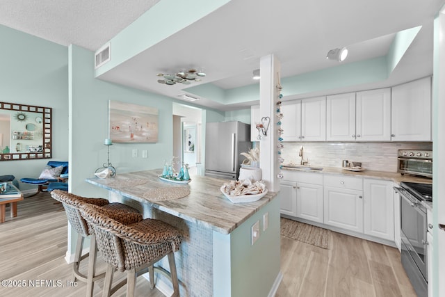 kitchen featuring a kitchen bar, sink, white cabinets, and appliances with stainless steel finishes