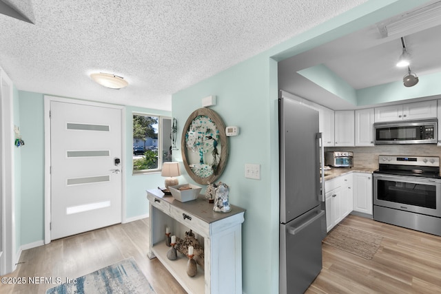 kitchen with white cabinetry, appliances with stainless steel finishes, a textured ceiling, and light hardwood / wood-style floors