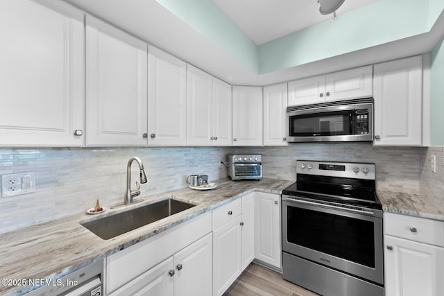 kitchen featuring tasteful backsplash, appliances with stainless steel finishes, sink, and white cabinets